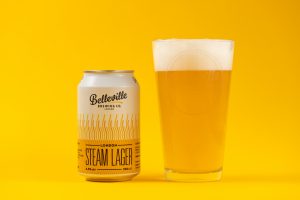 Christmas Beer and Food Pairings. Photograph of a can of Belleville London Stream Lager with a glass of golden coloured beer next to it on a yellow background