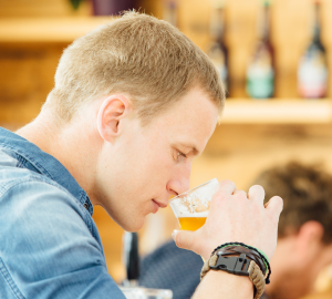 How to drink beer like a pro? Photograph of a young man smelling beer from the glass