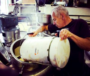 Deep Dive into Commonside Pale Ale. Photograph of Adrian from Belleville pouring a bucket of hops into a tank.